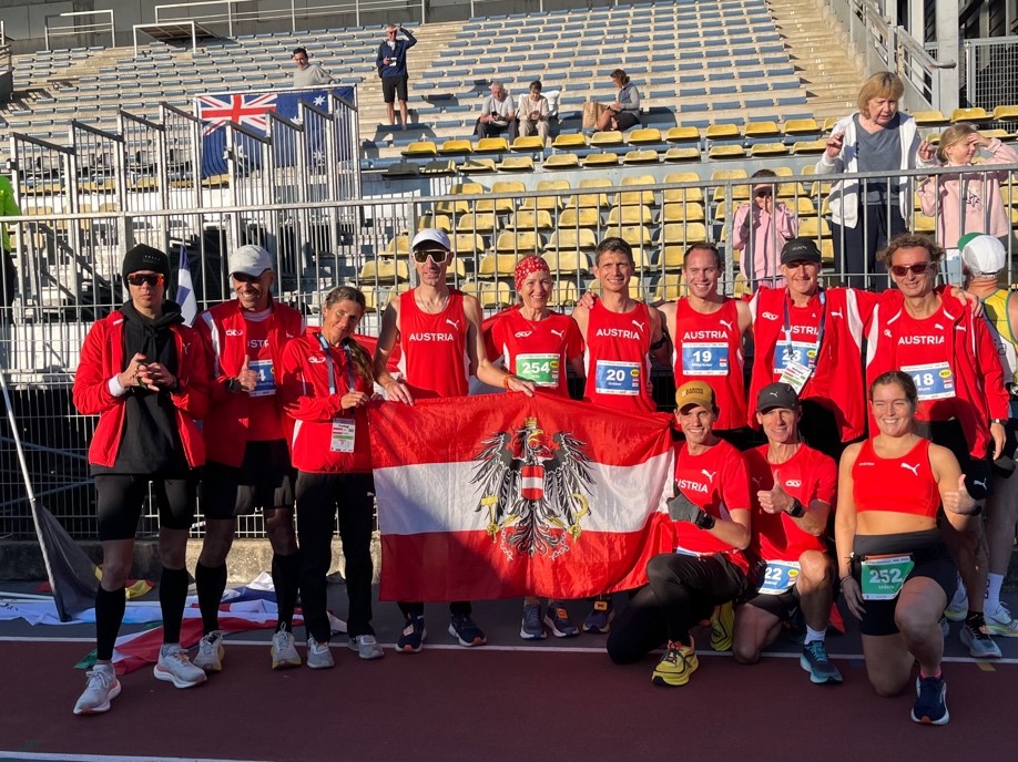 Das 12 Teilnehmer:innen starke österreichische Nationalteam in der Morgensonne vor dem Start, von links: Diana Dzaviza, Christian Vollenhofer-Rohlfing (beide Verein ULT Heustadlwasser), Karin Freitag (LG-Decker Itter), Mario Sturmlechner (Laufclub Mank), Ilse Fritz (ASKÖ Laufwunder Steyr), Stefan Greiner (#badischlläuft), Julian Mitteröcker (LC Waldviertel), Wolfgang Millinger (SK Maishofen), Harald Wurm (ULT Heustadlwasser); sowie hockend Rainer Predl (LC Strasshof), Markus Gabriel (LV-Marswiese) und Sabrina Lederle (ULT Heustadlwasser)